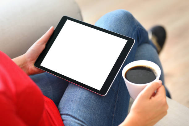 Using white screen tablet pc Woman using and touching a blank white screen tablet computer on a couch. preppy ideas stock pictures, royalty-free photos & images