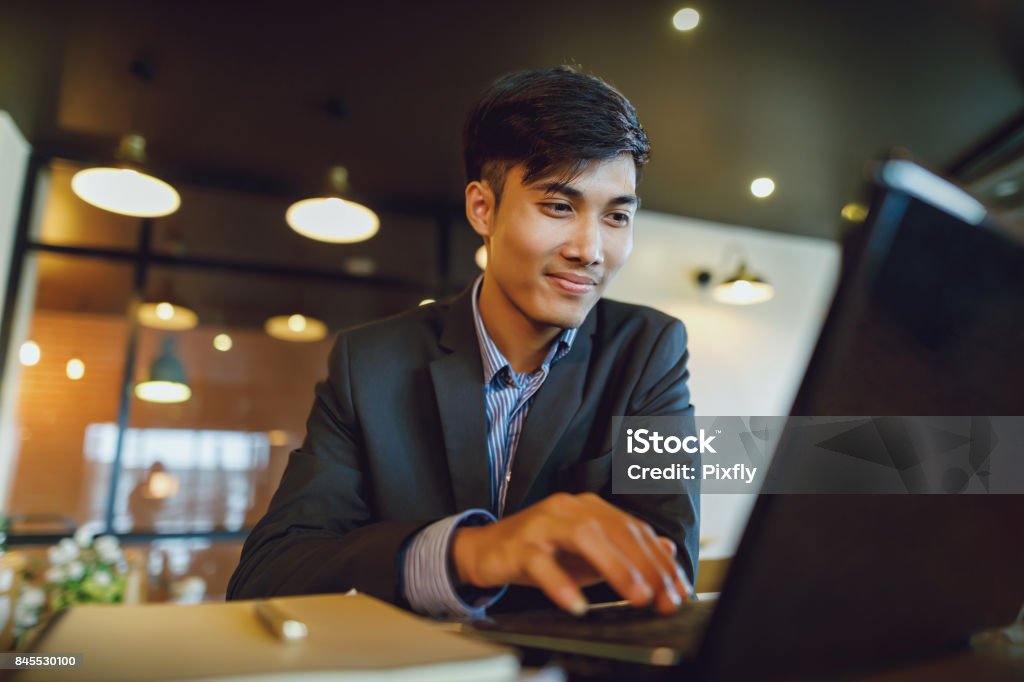 Sorridente uomo d'affari asiatico in giacca e cravatta che lavora con il laptop - Foto stock royalty-free di Filippine