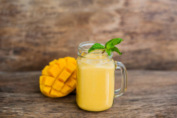 istock Mango smoothie in a glass Mason jar and mango on the old wooden background. Mango shake. 845537714