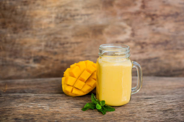 istock Mango smoothie in a glass Mason jar and mango on the old wooden background. Mango shake. 845537718