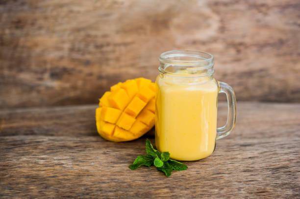 istock Mango smoothie in a glass Mason jar and mango on the old wooden background. Mango shake. 845537724