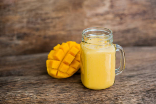 istock Mango smoothie in a glass Mason jar and mango on the old wooden background. Mango shake. 845537726