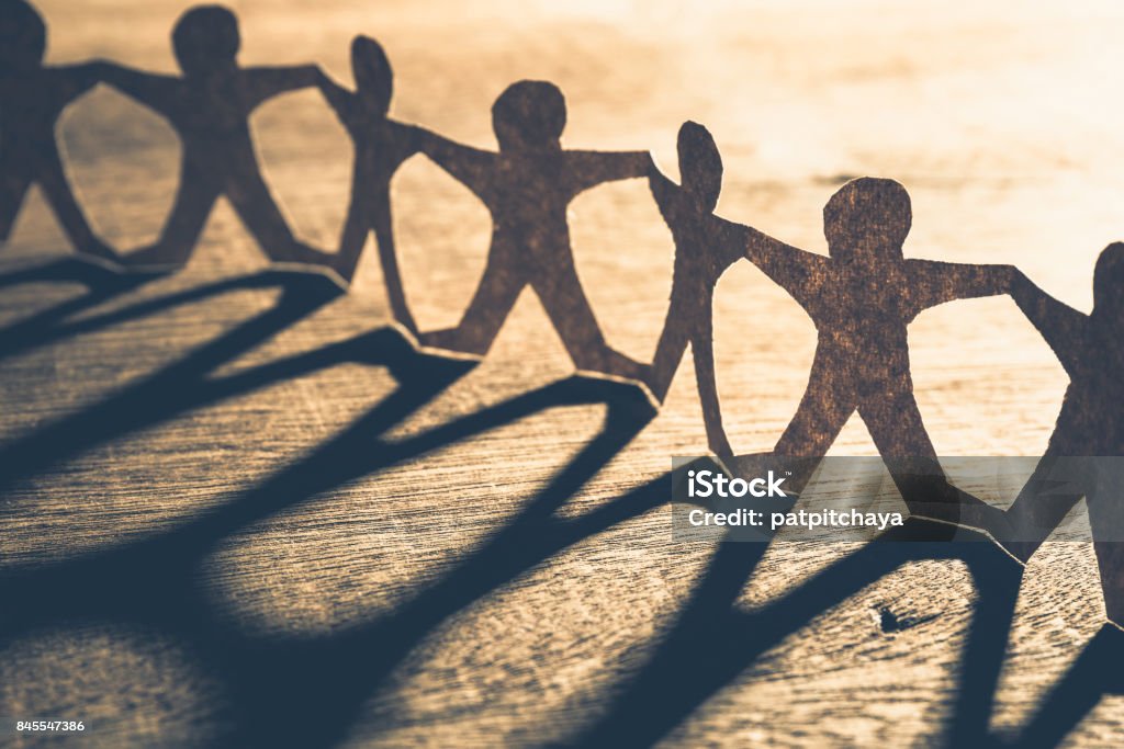 Human Chain Paper Human chain paper with light and shadow on wood table People Stock Photo