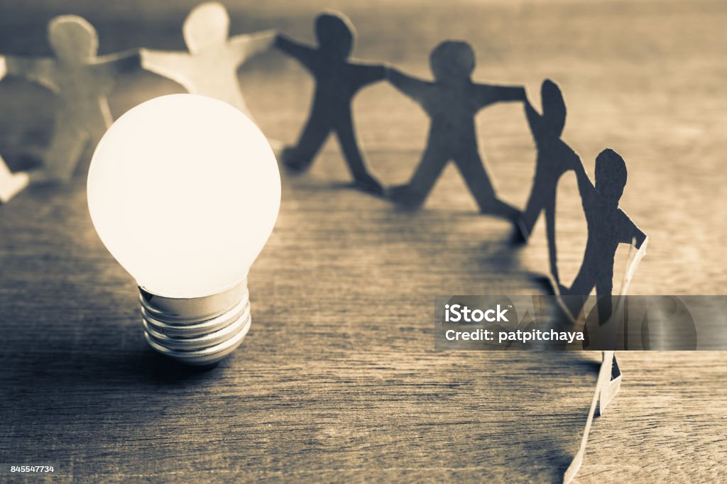 Success Teamwork Glowing light bulb with human chain paper Light Bulb Stock Photo