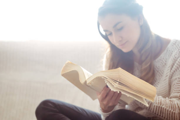 istock girl reading a book closeup on the sofa 845555560