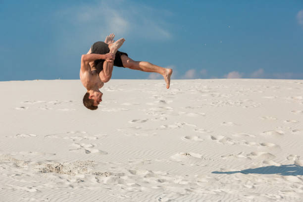 retrato de hombre joven parkour haciendo flip o voltereta en la arena - back somersault fotografías e imágenes de stock