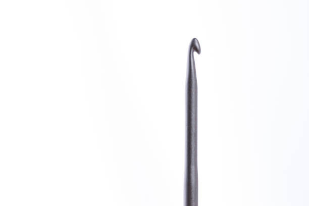 Golden 6.0 mm crochet hook placed diagonally on a dark blue textile background with plenty of copy space.