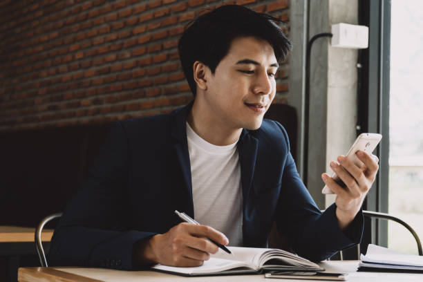 istock Businessman using smart phone and writing in organizer. 845580028