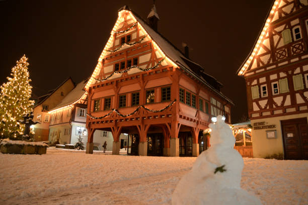 Christmas in Plochingen (Baden-Württemberg - Germany); festively lit, snow-covered pedestrian zone: market square, fountain, fountain sculptures, old town hall, early knife house, Ottilienkapelle, snowman