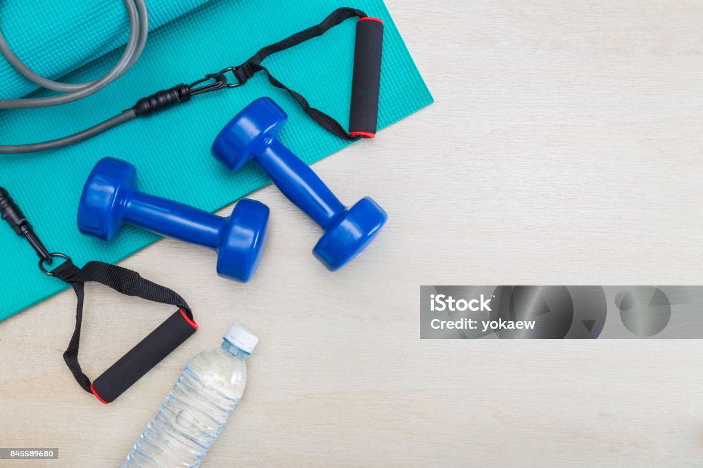 dumbbells, exercise equipment, gym yoga mat, and bottle of water on clean wood floor, healthy and well being concept, with room for text or copy space Gym Stock Photo