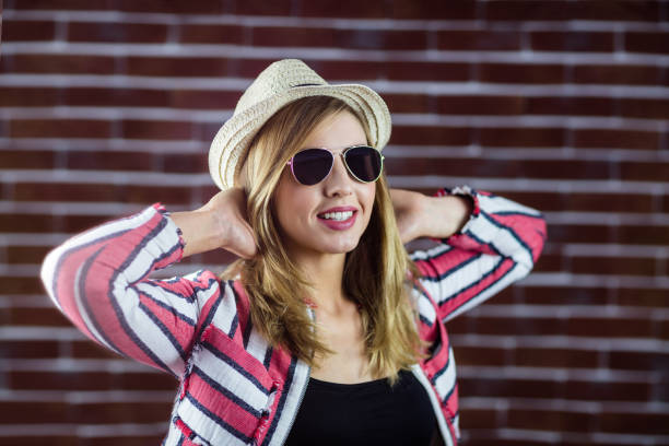 Smiling woman wearing sunglasses while stretching herself
