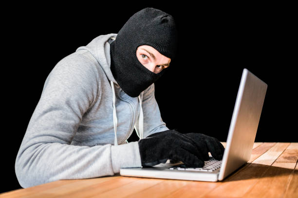 istock Focused thief with hood typing on laptop 845609008