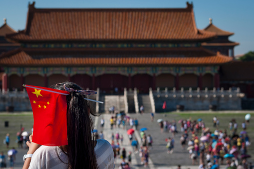 Beijing, China - July 29, 2012: Young Chinese girl with a Chinese Flag in her head at the Forbidden City in the city of Beijing, in China