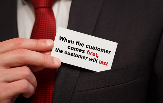 Businessman putting a card with text When the customer comes first the customer will last in the pocket
