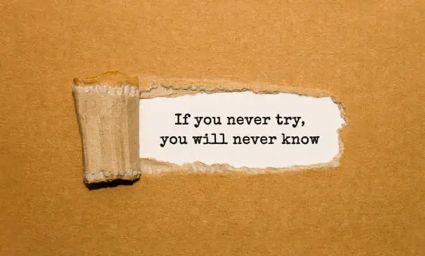 The text If you never try you will never know appearing behind torn brown paper