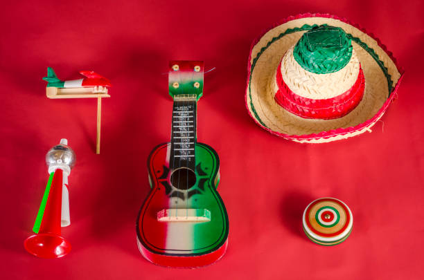 Yo yo,guitar,toy trumpet and noisemaker against red background. Accessories for mexican Independence Day celebration