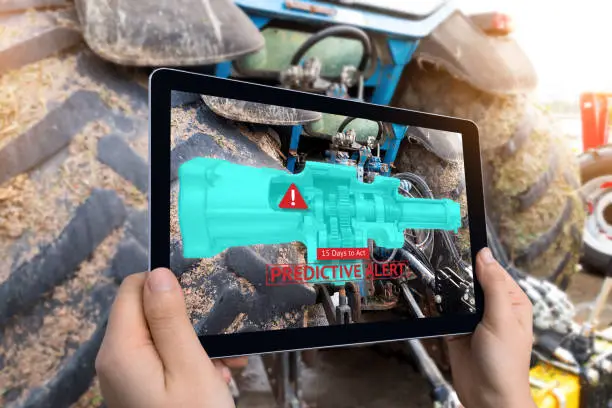 Industrial 4.0 , Augmented reality technology , smart agriculture and farm concept. Hand holding tablet with AR maintenance application and predictive alert for check destroy part of smart machine.