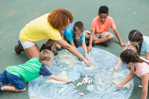 camp counselor with children, chalk drawing of earth - child chalking imagens e fotografias de stock