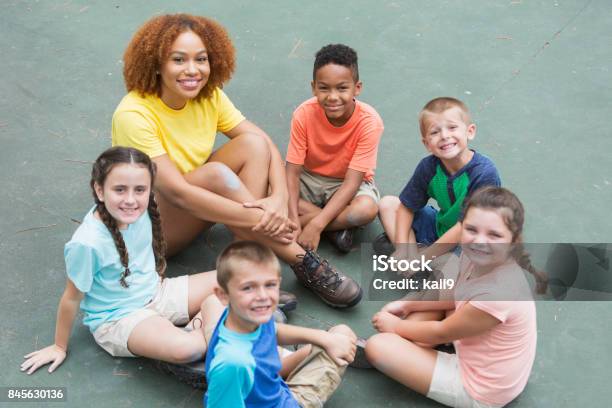 Photo libre de droit de Conseiller De Camp Multiethniques Enfants Assis En Cercle banque d'images et plus d'images libres de droit de Animateur de colonie de vacances