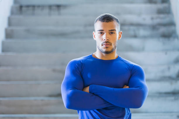Young, muscular, mixed race man Portrait of a young, mixed race man with a muscular build, standing, looking at the camera with his arms crossed, He is African-American and Native American. metrosexual stock pictures, royalty-free photos & images