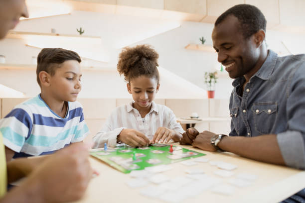 african-american family playing board game in cafe african-american family playing board game in cafe the black womens expo stock pictures, royalty-free photos & images