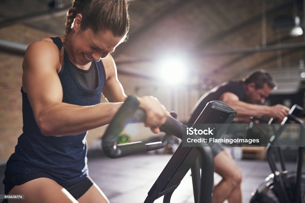 Deportistas trabajando en máquinas de ciclo - Foto de stock de Ejercicio físico libre de derechos