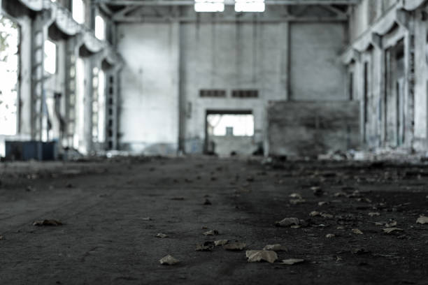Interior of old factory buildings destroyed. Ruins of industrial enterprise, dark debris destroyed factory premises in factory as result of economic crisis and earthquake.