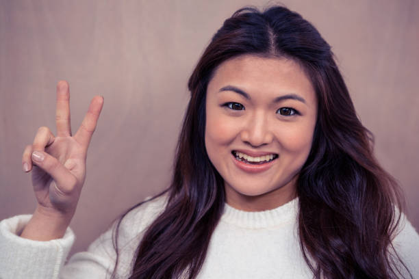 istock Smiling Asian woman making peace sign 845665112