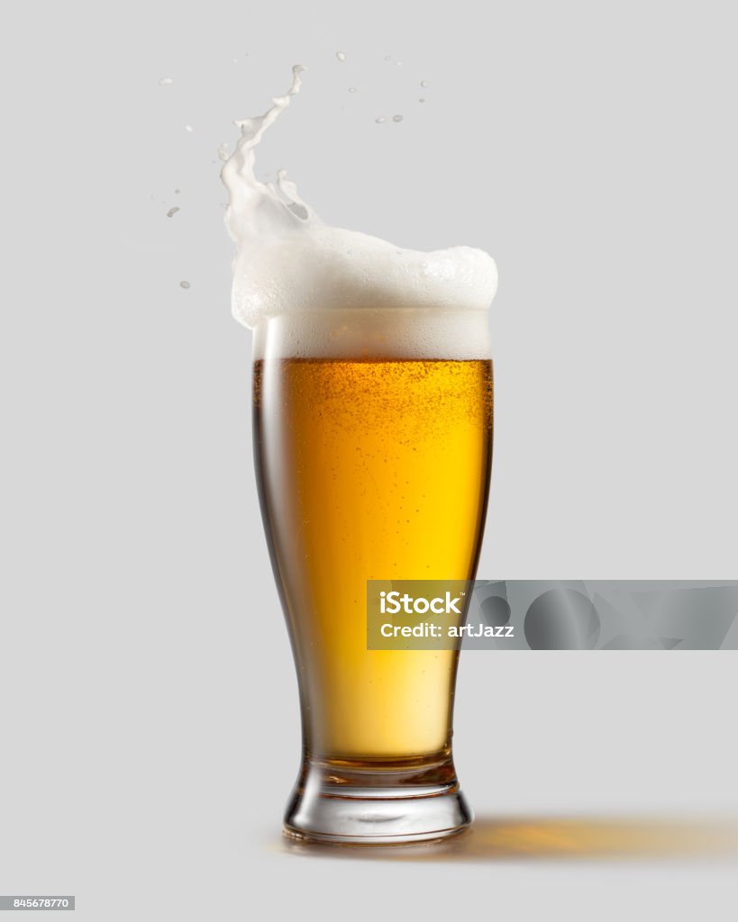 Frosty glass of light beer with foam Frosty glass of light beer with foam and splashes, isolated on gray background Beer - Alcohol Stock Photo