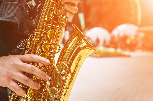 Close-up of the hand of a street musician playing the saxophone, selective focus, toned, copy space