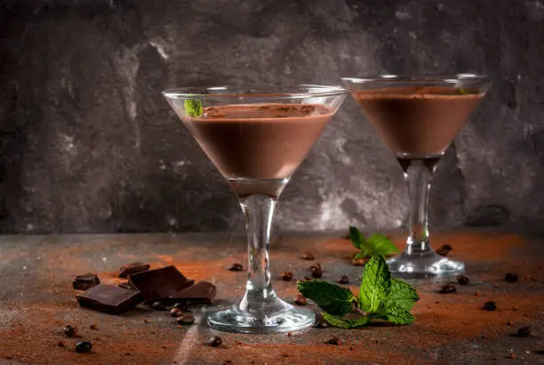 Cream coffee cocktail, chocolate martini with mint on black stone table, copy space