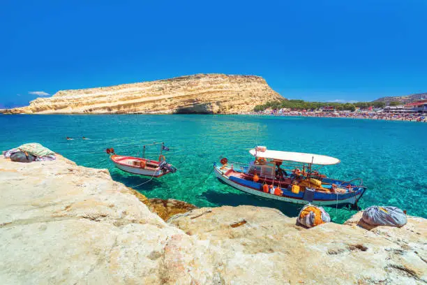 Matala beach with old fishing boats and caves on the rocks that were used as a roman cemetery and at the decade of 70's were living hippies from all over the world, Crete, Greece