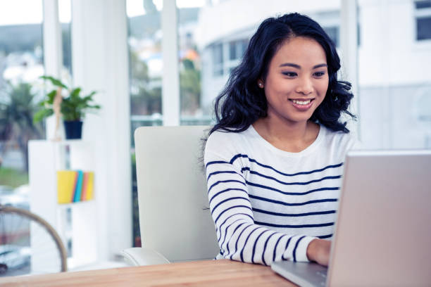 smiling asian woman using laptop - job search fotos imagens e fotografias de stock