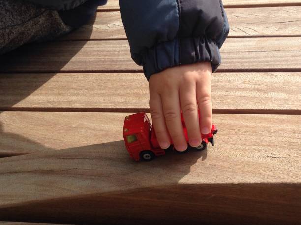 istock Child Playing with Red Car on Wooden Bench Outdoors in London 845708994