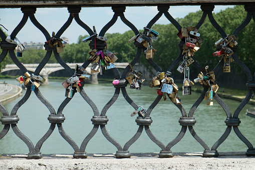 Love padlocks hanging in a row on a bridge railing in Roma, Italy
