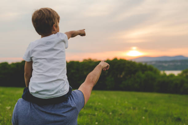 istock Father and son having fun outdoors in the meadow sunset pointing 845715082