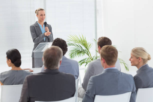 istock Pretty businesswoman talking in microphone during conference 845725476
