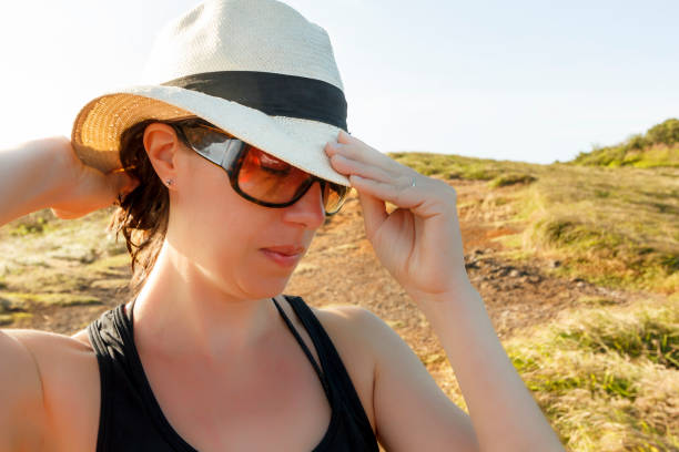 A DSLR Canon photo of 38-year-old Brazilian woman holding a straw hat on her head.
