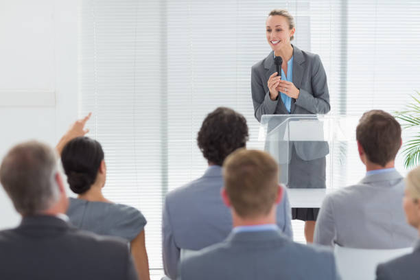 istock Pretty businesswoman talking in microphone during conference 845736302