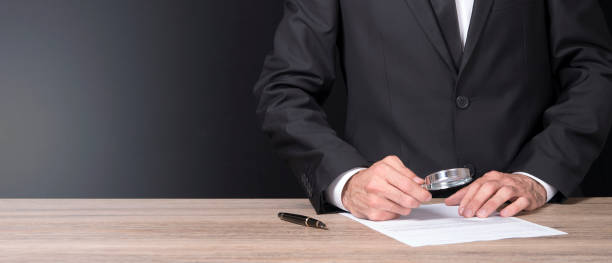 istock businessman is analyzing the document with a magnifying glass 845739508