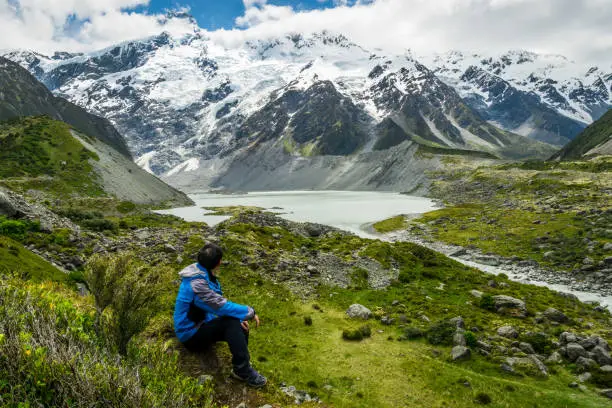 Mountain hiker traveling in wilderness landscape of Mt Cook National Park. Mt Cook, the highest mountain in New Zealand, is known for outdoor travel trekking inspiration, mountain journey.