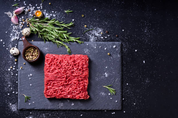 Raw fresh marbled mince meat and seasonings on dark background. Raw fresh marbled mince meat and seasonings on dark background. Copy space, high angle view. salisbury steak stock pictures, royalty-free photos & images