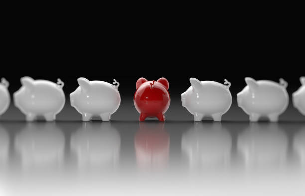 Piggy banks forming a horizontal line. The piggy bank in the middle is in red color and turning its back to the camera. Standing out from the crowd concept. Horizontal composition with copy space.