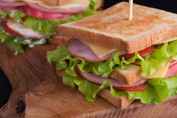 ハム、チーズ、トマト、暗い背景にトーストしたパンにサラダと大きなサンドイッチをクローズ アップ - toasted sandwich close up color image panini ストックフォトと画像