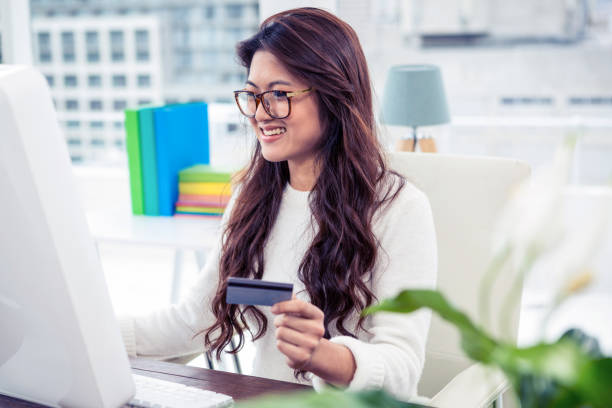 istock Smiling Asian woman on computer holding credit card 845760796