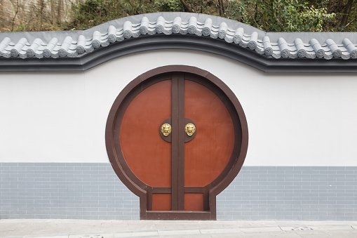 A Moon Gate is a circular opening in a garden wall that acts as a pedestrian passageway, and a traditional architectural element in Chinese gardens.