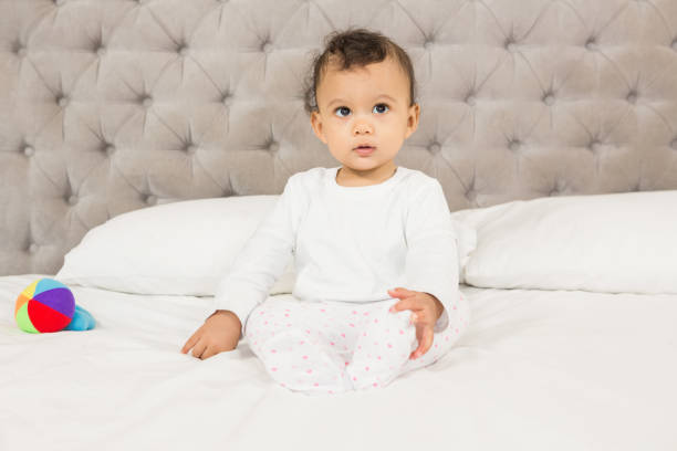 istock Cute baby sitting on bed 845766528
