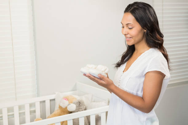 istock Smiling brunette holding baby shoes 845766782