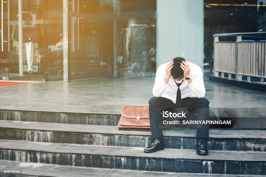 Paro cansado o estresado hombre de negocios sentado en el pasillo después del trabajo concepto de empresario Stressed - Foto de stock de Desempleo libre de derechos