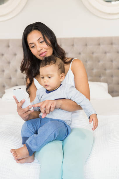 istock Happy brunette holding her baby and using smartphone 845773162